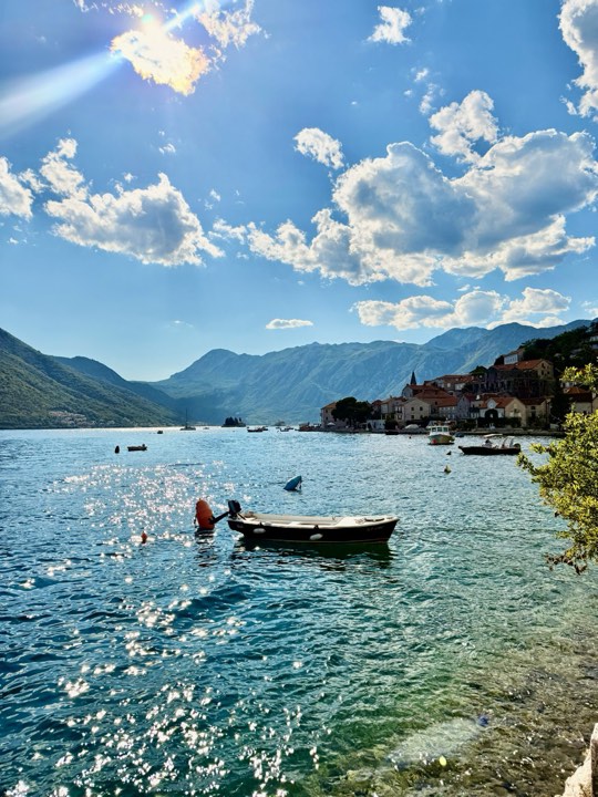 A small boat on the bay with mountains behind