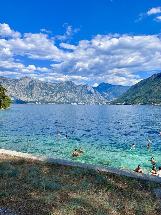 Swimmers in crystal clear water beside the promenade